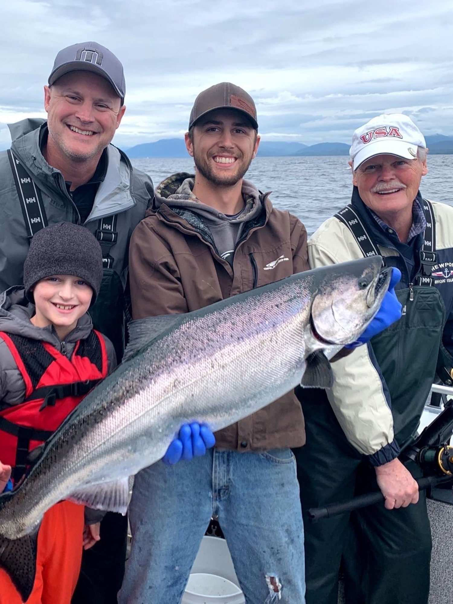 Captain Aaron of Ketchikan fishing holding a large fish that two adult males and one child caught on a fishing trip.