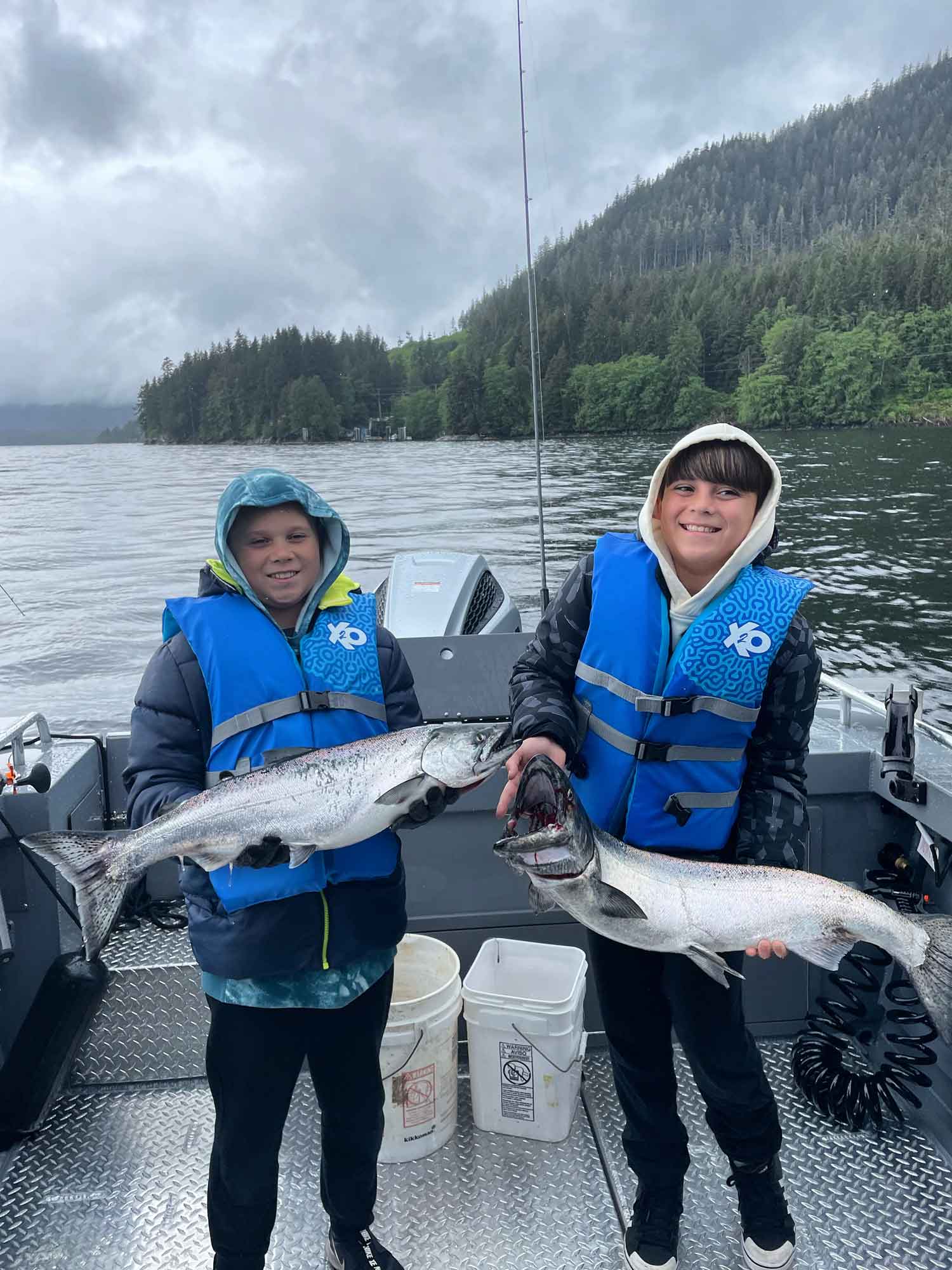 Two boys holding salmon they caught.