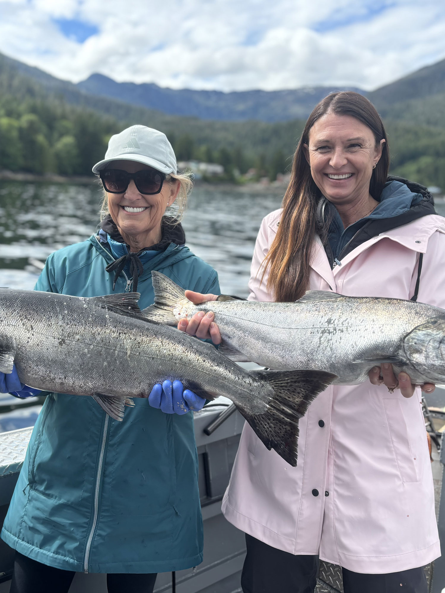 Two friends holding their Salmon catch on Ketchikan fishing charter in Alaska.
